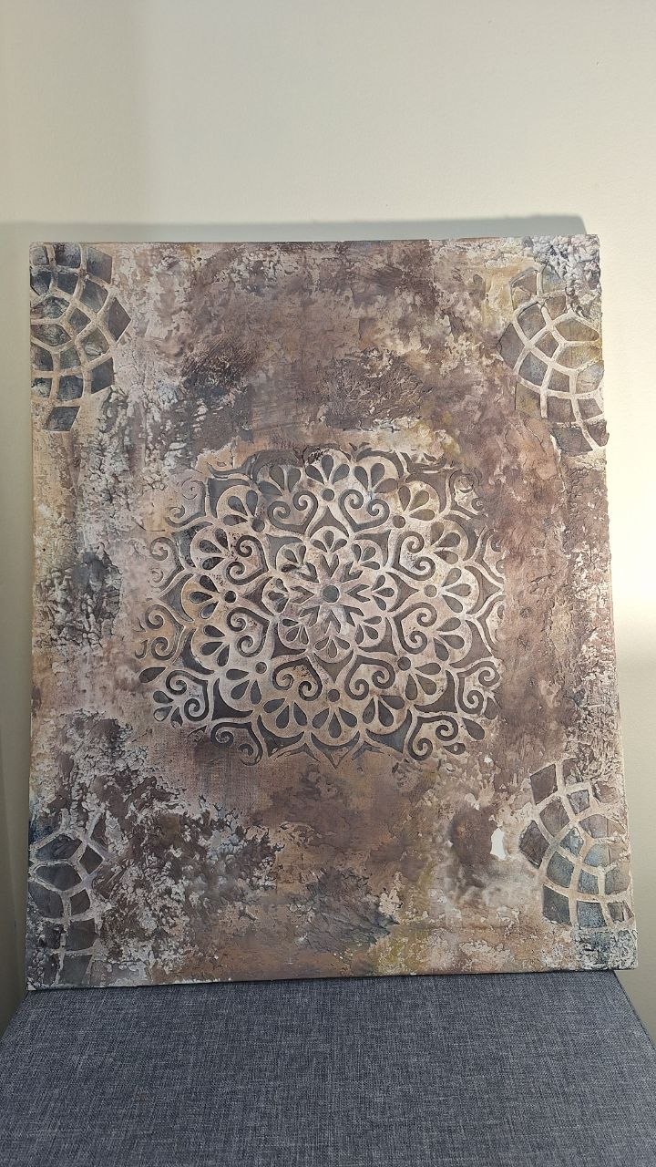 Earth-toned textured artwork with a central ornamental mandala