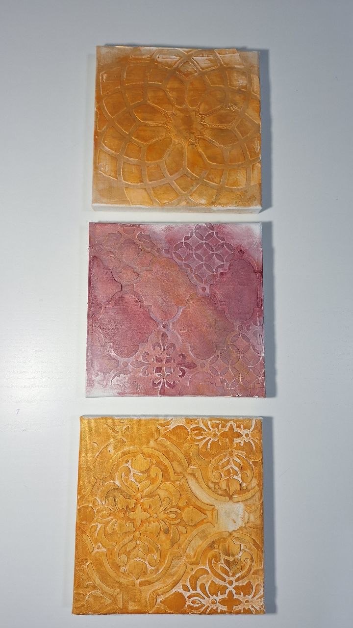 Three small textured artworks in ochre and dusty rose