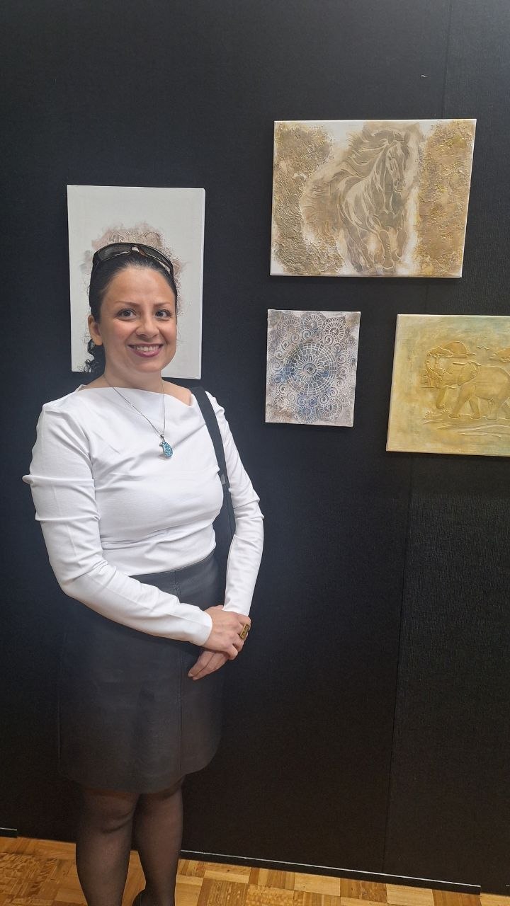 Shabnam standing beside her artworks at an exhibition